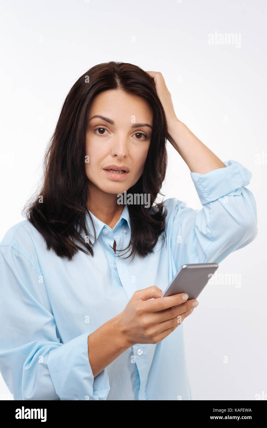 Dunkelhaarige Frau umklammert den Kopf nach dem Lesen der schlechten Nachrichten Stockfoto