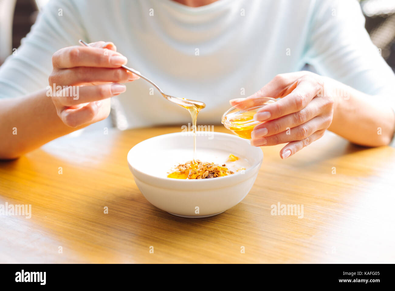 Weibliche Hände Honig Gießen zu Haferflocken Stockfoto