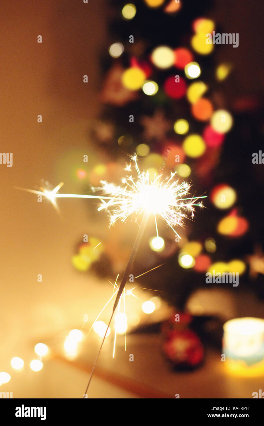 Sparkle Stick mit Lichtern und Weihnachtsbaum auf dem Hintergrund Stockfoto