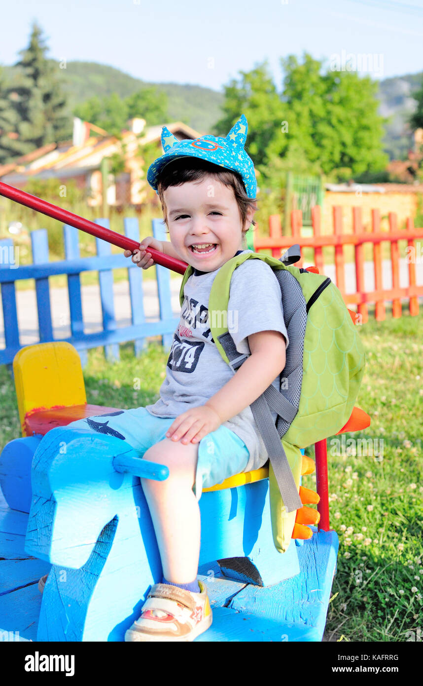 Happy little boy genießt die Fahrt auf den Kreisverkehr an einem sonnigen Tag Stockfoto