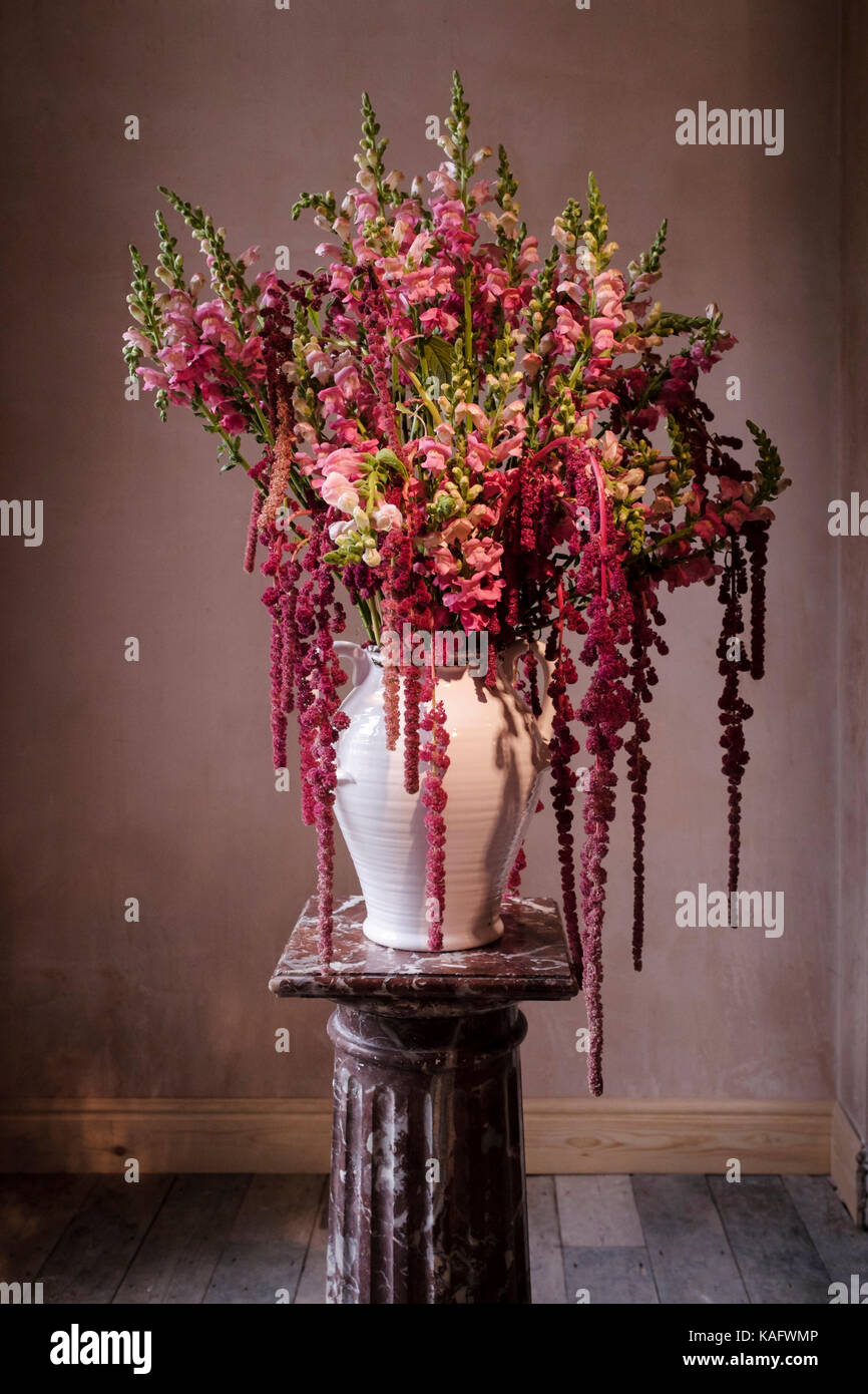 Aufwendige Blumenschmuck auf Marmor Werk stand in schmucklose Zimmer angezeigt. Stockfoto