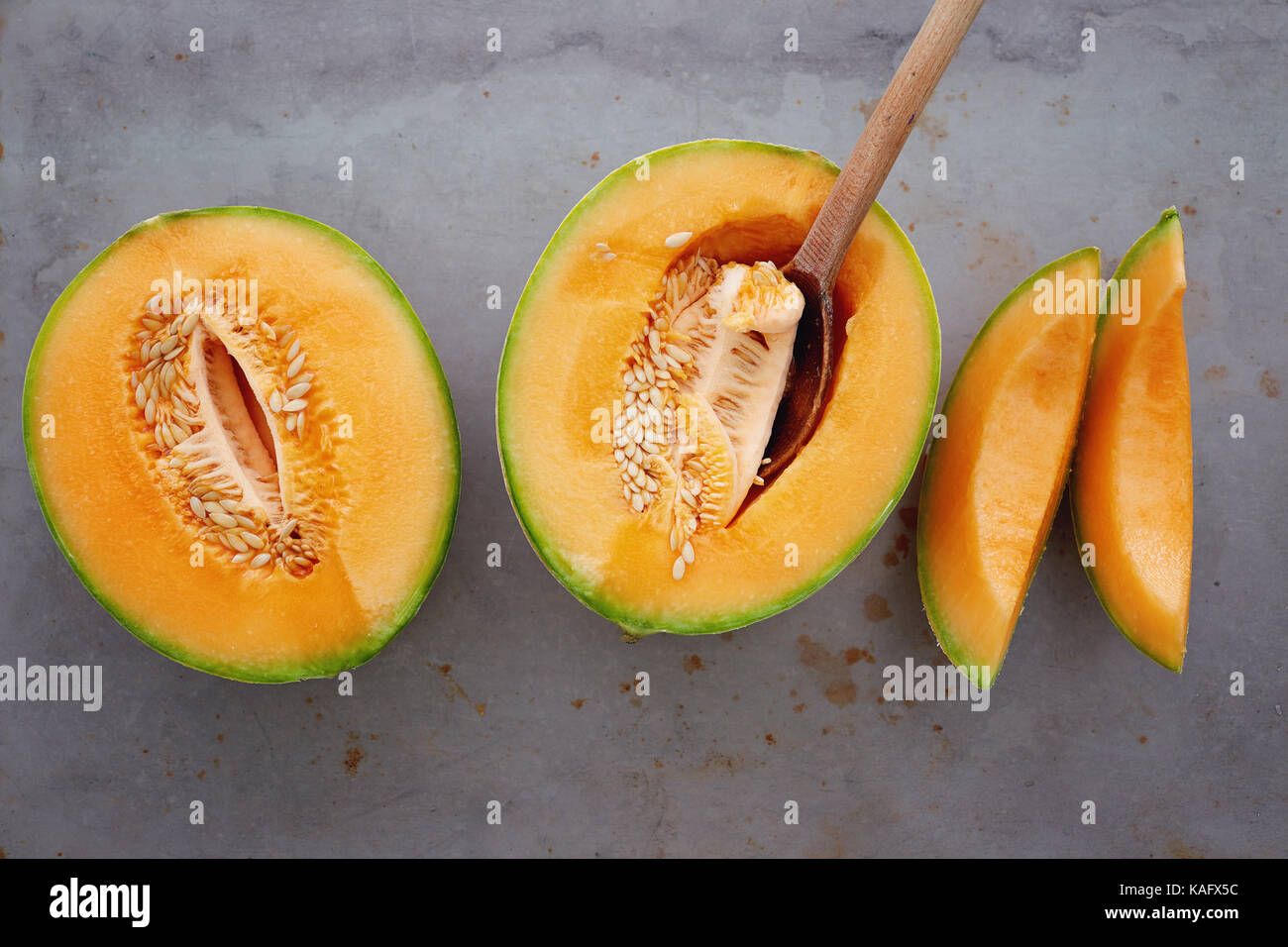 Frische Melone in kleine Stücke schneiden. Die Hälfte der Reife Zuckermelone mit Löffel. Stockfoto