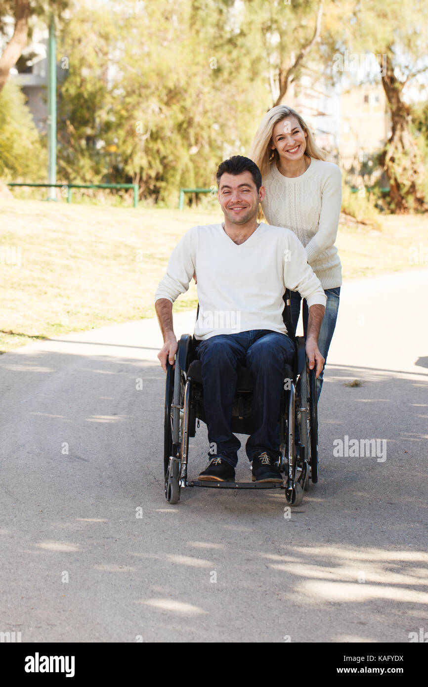 Behinderte Menschen im Rollstuhl zu Fuß mit seiner Freundin im Park Stockfoto