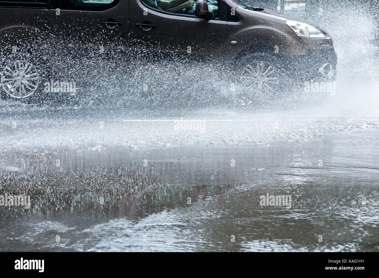Autofahrten durch Regen Pfützen auf nasser Straße mit Spritzwasser. Stockfoto