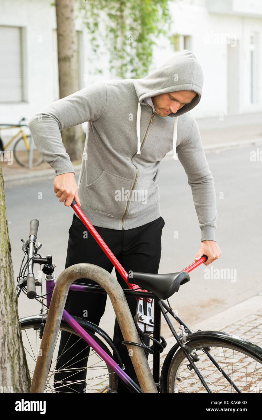 Dieb versucht, das Fahrradschloss zu brechen in der Nähe der Straße geparkt Stockfoto