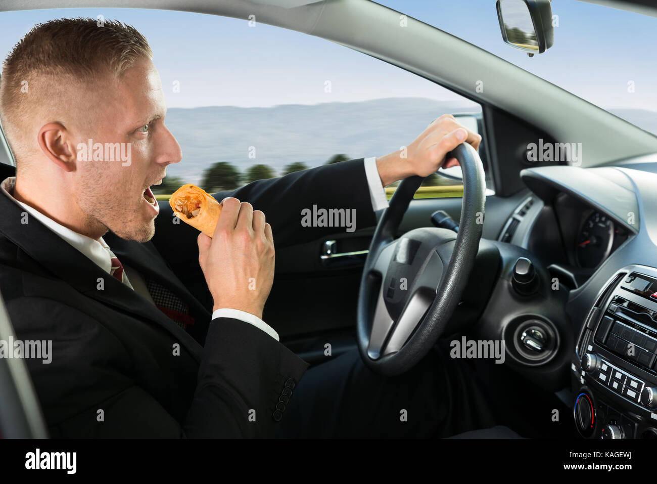 Nahaufnahme eines Junge Unternehmer essen Snack während der Fahrt Stockfoto