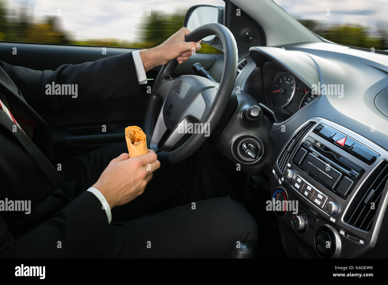 Nahaufnahme eines männlichen Holding Snack während der Fahrt in seinem Auto Stockfoto
