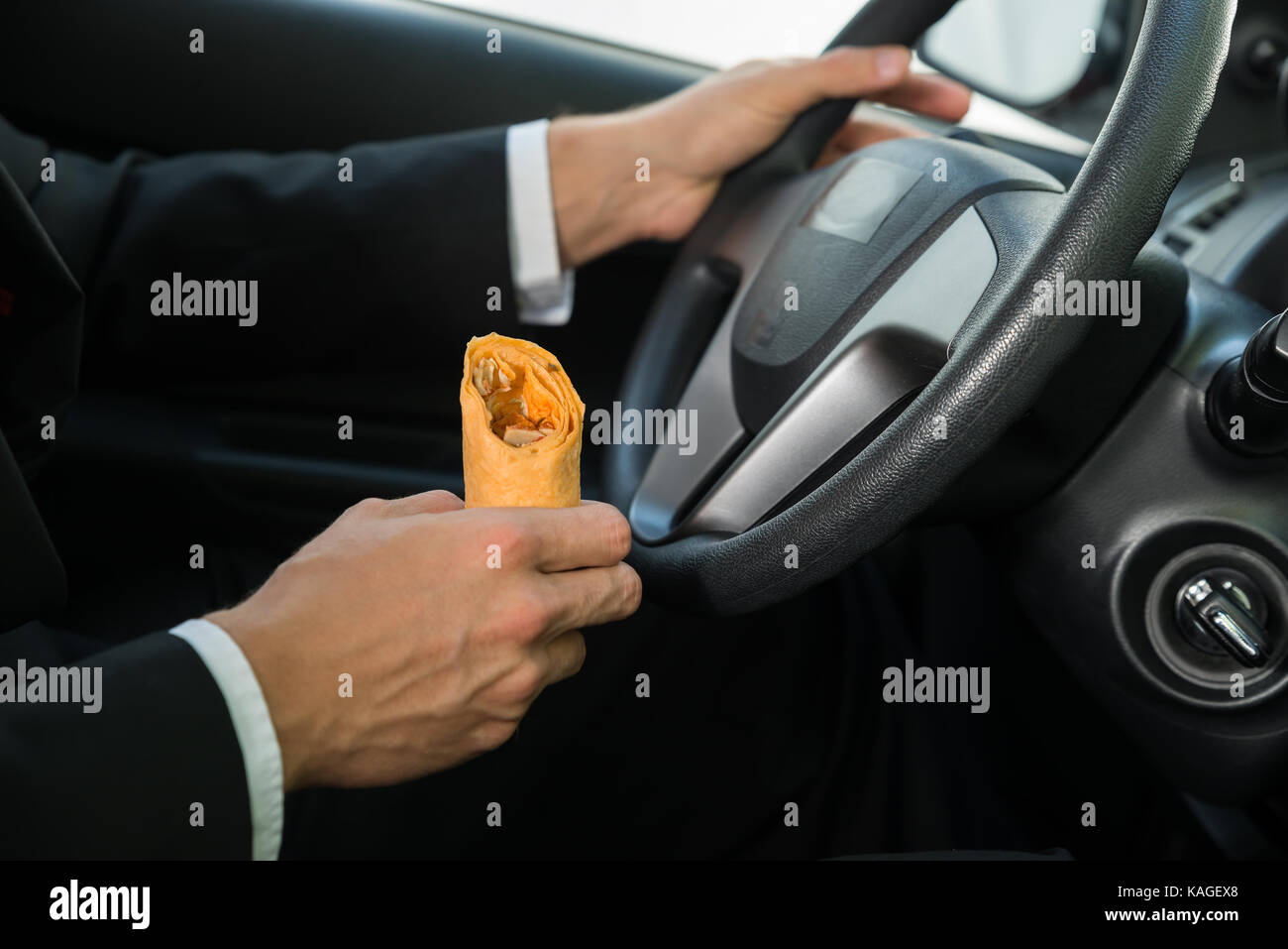 Nahaufnahme eines männlichen Holding Snack während der Fahrt in seinem Auto Stockfoto