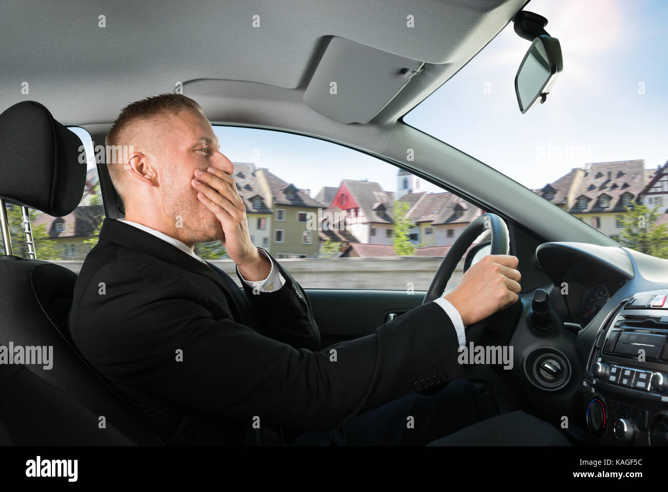 Portrait einer jungen Geschäftsmann Gähnen während der Fahrt Auto Stockfoto