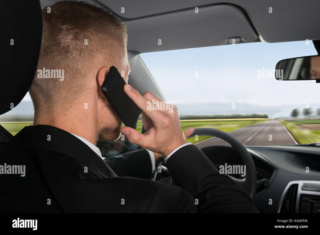 Ansicht der Rückseite ein Geschäftsmann mit Mobiltelefon während der Fahrt Auto Stockfoto