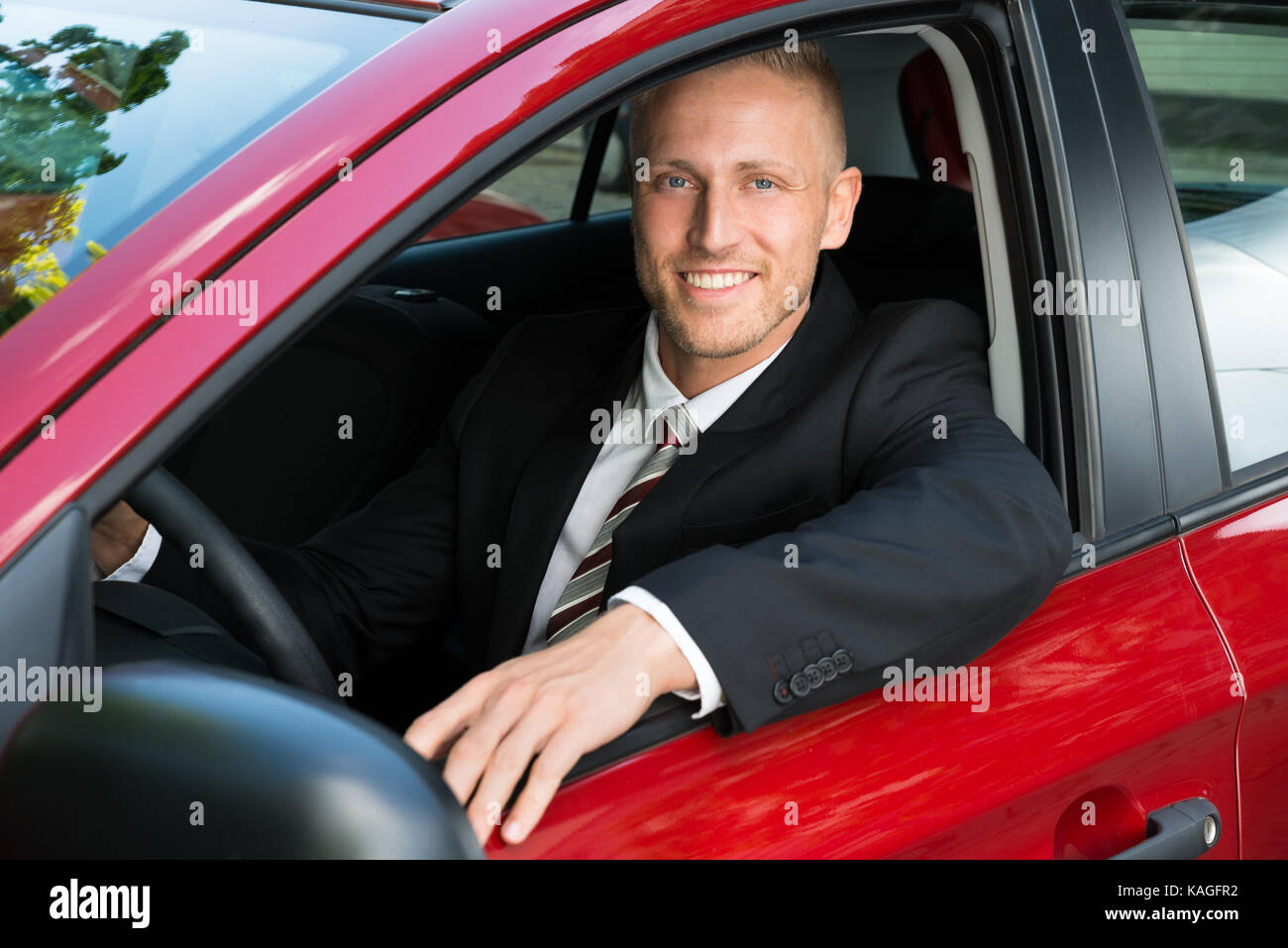 Portrait Of Happy Kaufmann in seinem neuen Auto sitzen Stockfoto