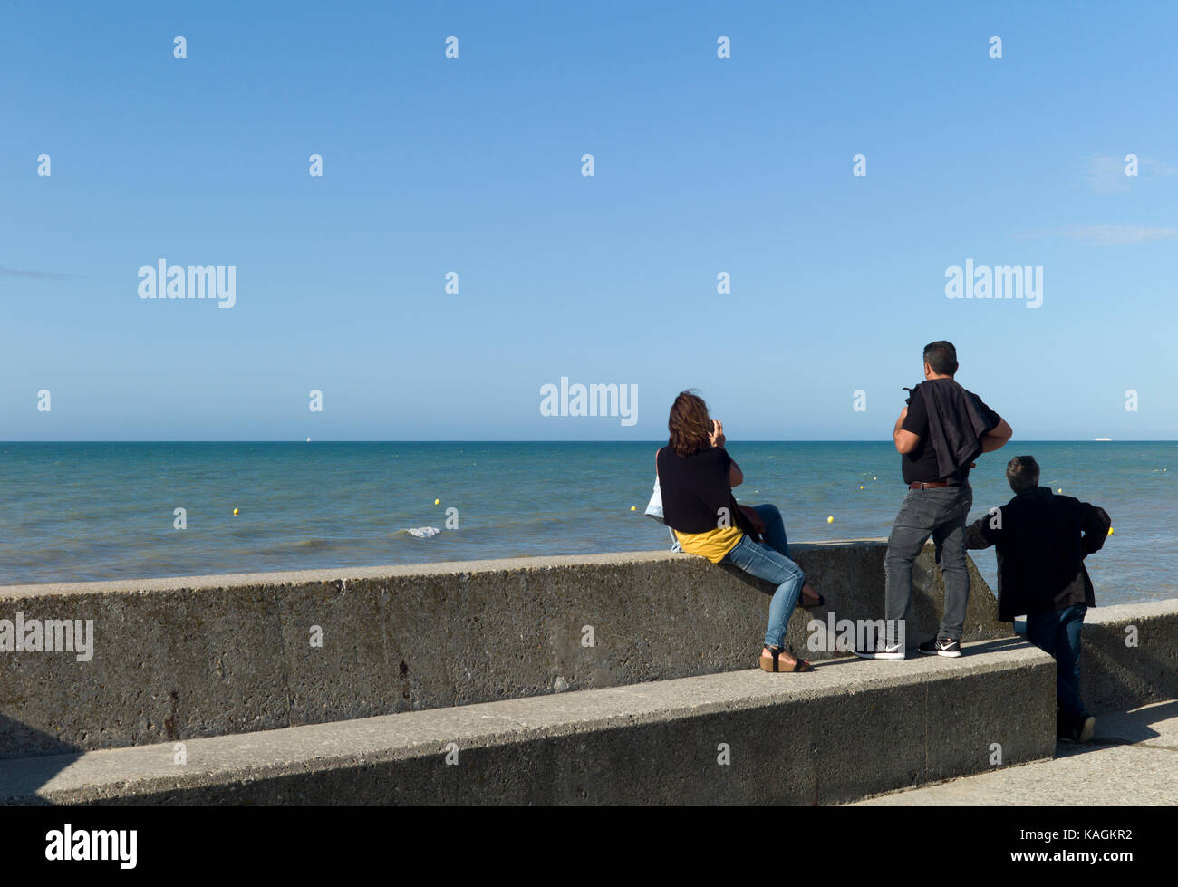Drei Leute auf einem Sea Wall, Normandie, Frankreich Stockfoto
