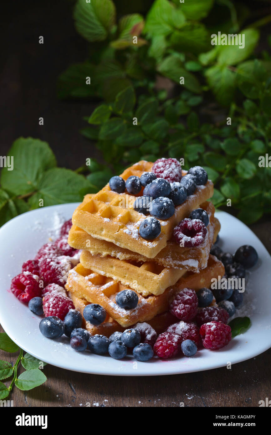 Leckere süße Waffeln mit Himbeeren und Blaubeeren auf einem alten ...