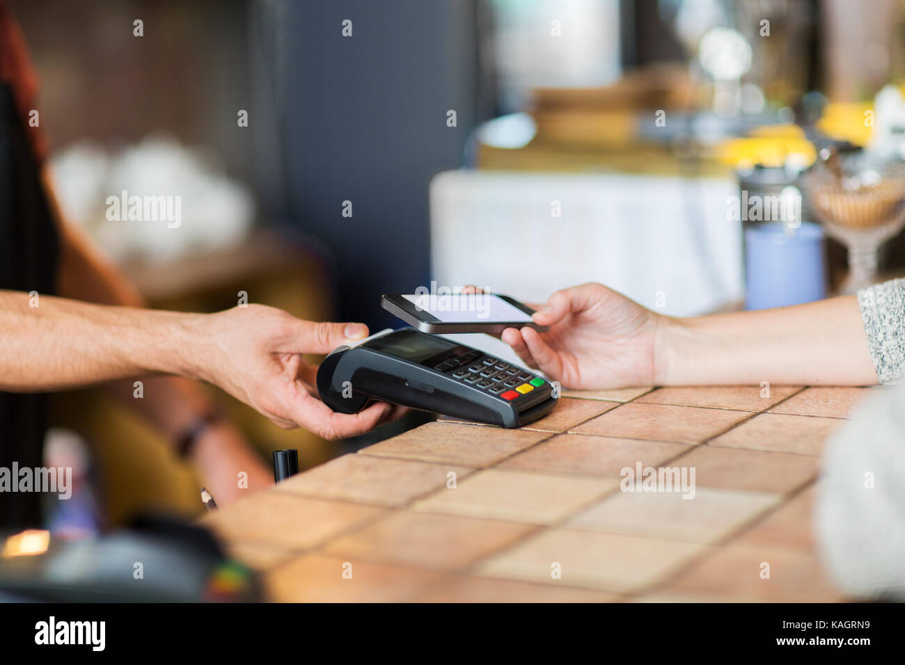 Hände mit Payment Terminal und Smartphone in der Bar Stockfoto