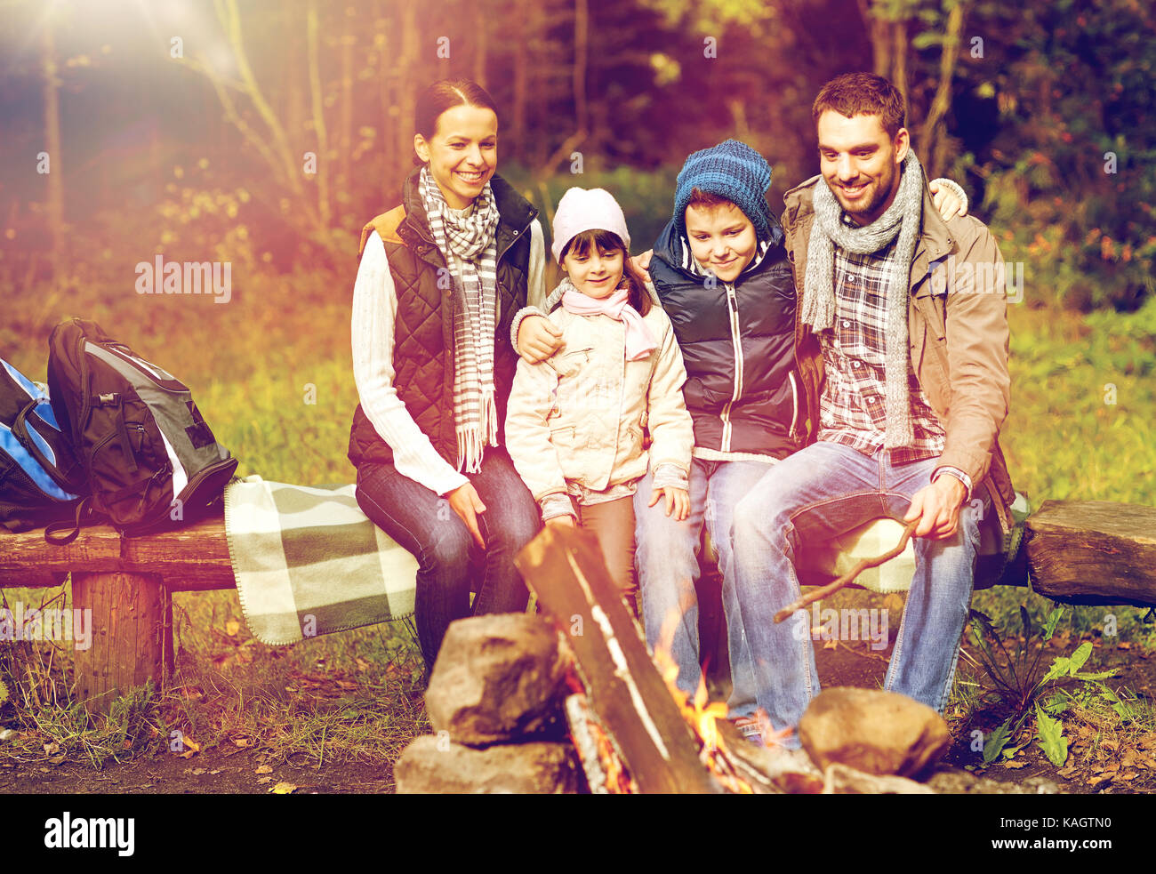 Glückliche Familie sitzt auf der Bank am Lagerfeuer. Stockfoto