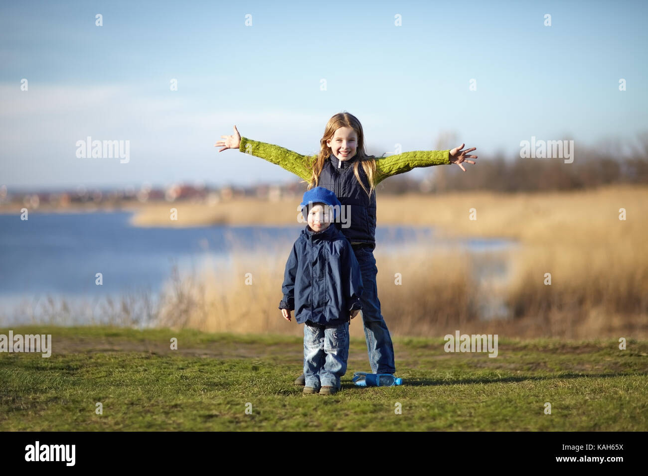 Junge glücklich Verbreitung Hände mit jüngeren Bruder neben dem Fluss. Glücklich lifestyle Kids Stockfoto