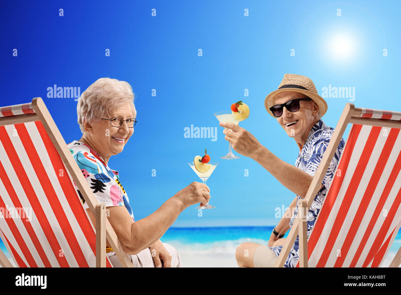 Ältere Touristen mit Cocktails in Liegestühlen am Strand Stockfoto