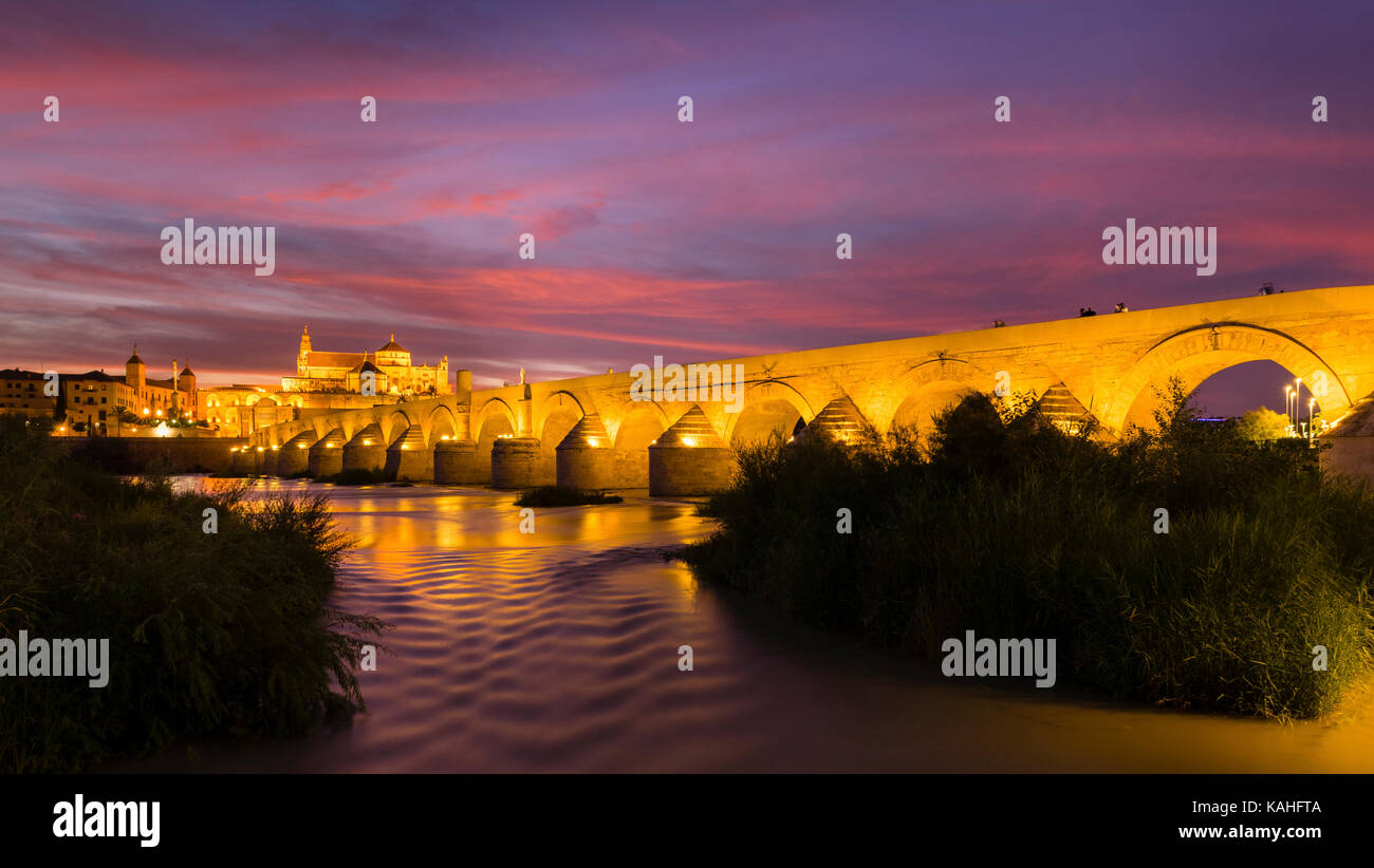 Beleuchtete Puente Romano, römische Brücke über Rio Guadalquivir, hinten Mezquita, Catedral de Córdoba, Abenddämmerung, Cordoba, Andalusien Stockfoto