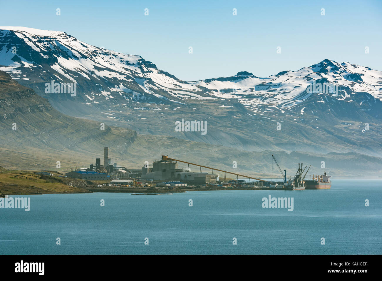 Aluminiumhütte vor schneebedeckten Bergen, Reyðarfjörður, Ostfjorde, Insel Stockfoto