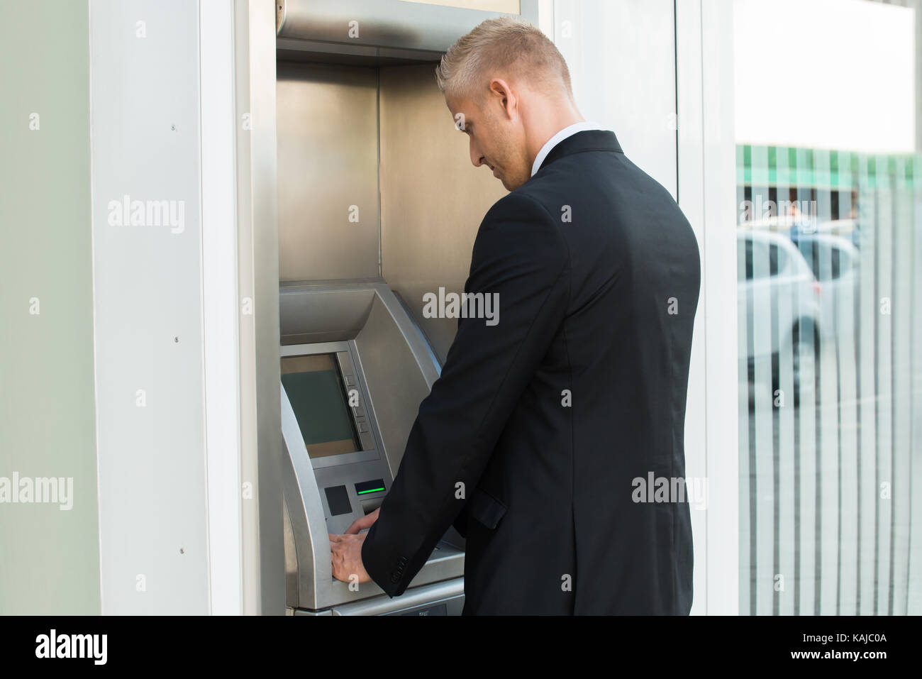 Junger Mann mit Geldautomaten abheben Geld Stockfoto