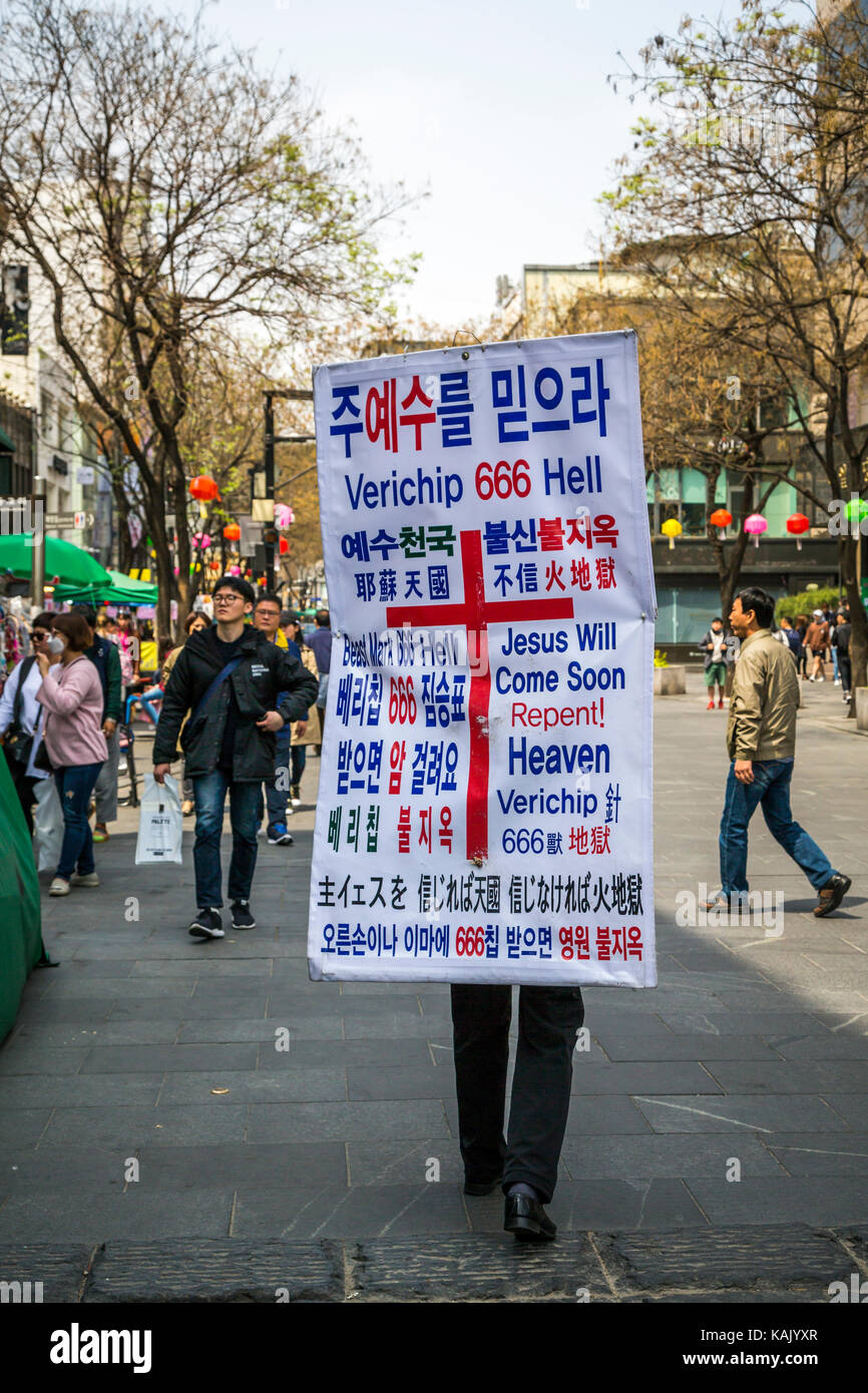 Ein Mann, der einen religiösen Plakat entlang Insadong-gil Straße im Stadtteil Insadong von Seoul, Südkorea, Asien. Stockfoto