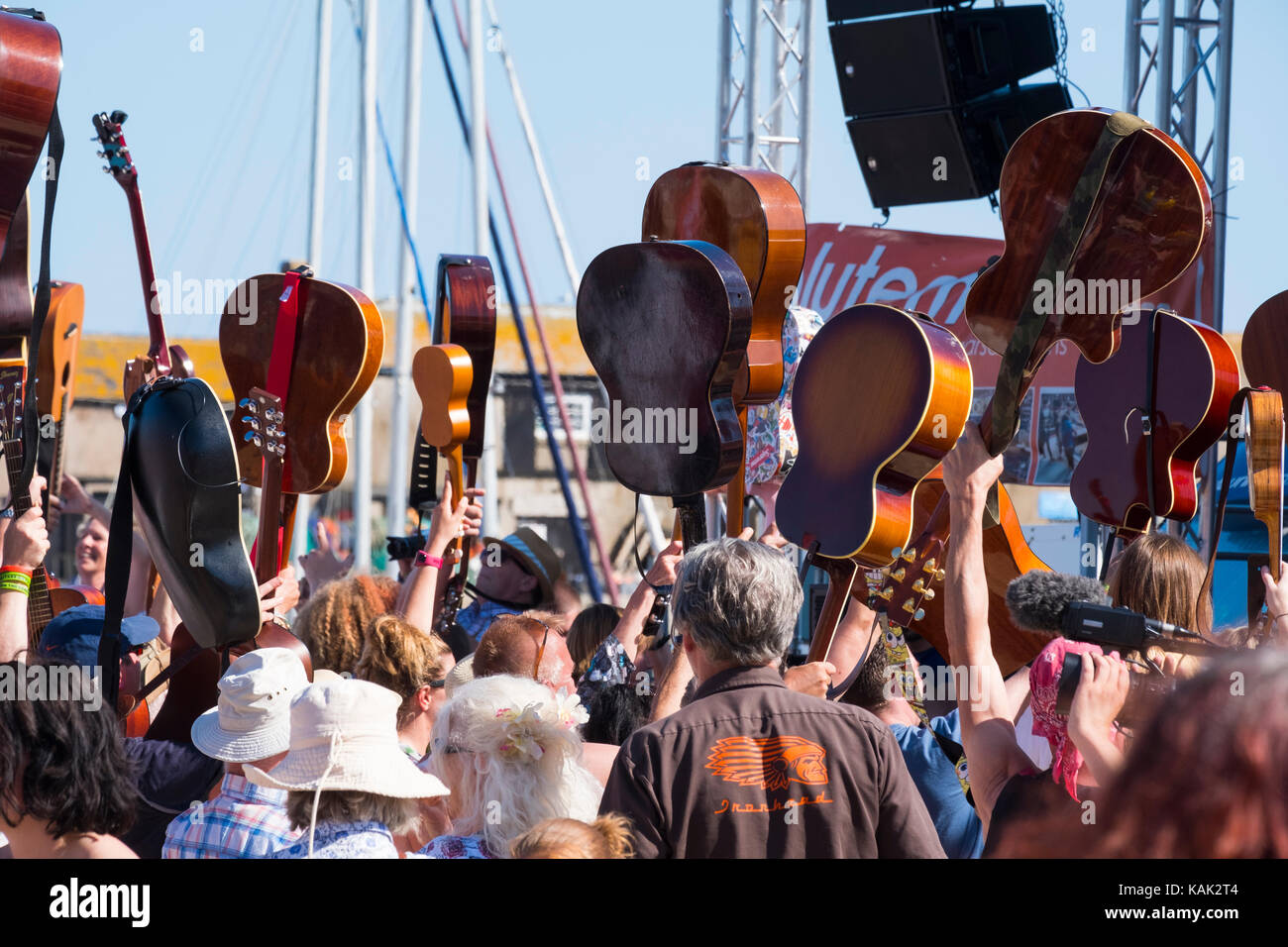 Die Gitarristen ihre Instrumente aloft während die Gitarren am Strand Veranstaltung in Lyme Regis, Dorset, Großbritannien. Stockfoto