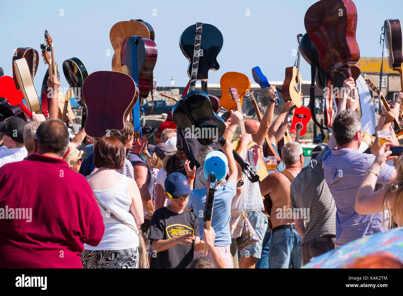 Die Gitarristen ihre Instrumente aloft während die Gitarren am Strand Veranstaltung in Lyme Regis, Dorset, Großbritannien. Stockfoto