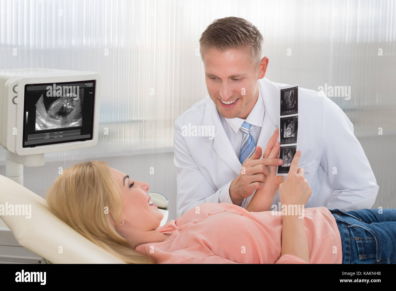 Junge männliche Arzt erklären Ultraschall für schwangere Frau Scan im Krankenhaus Stockfoto