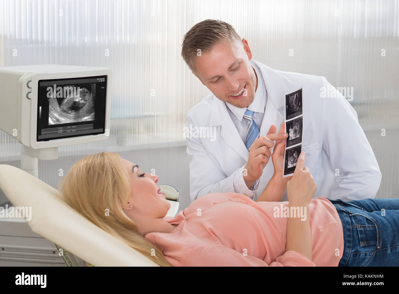 Junge männliche Arzt erklären Ultraschall für schwangere Frau Scan im Krankenhaus Stockfoto