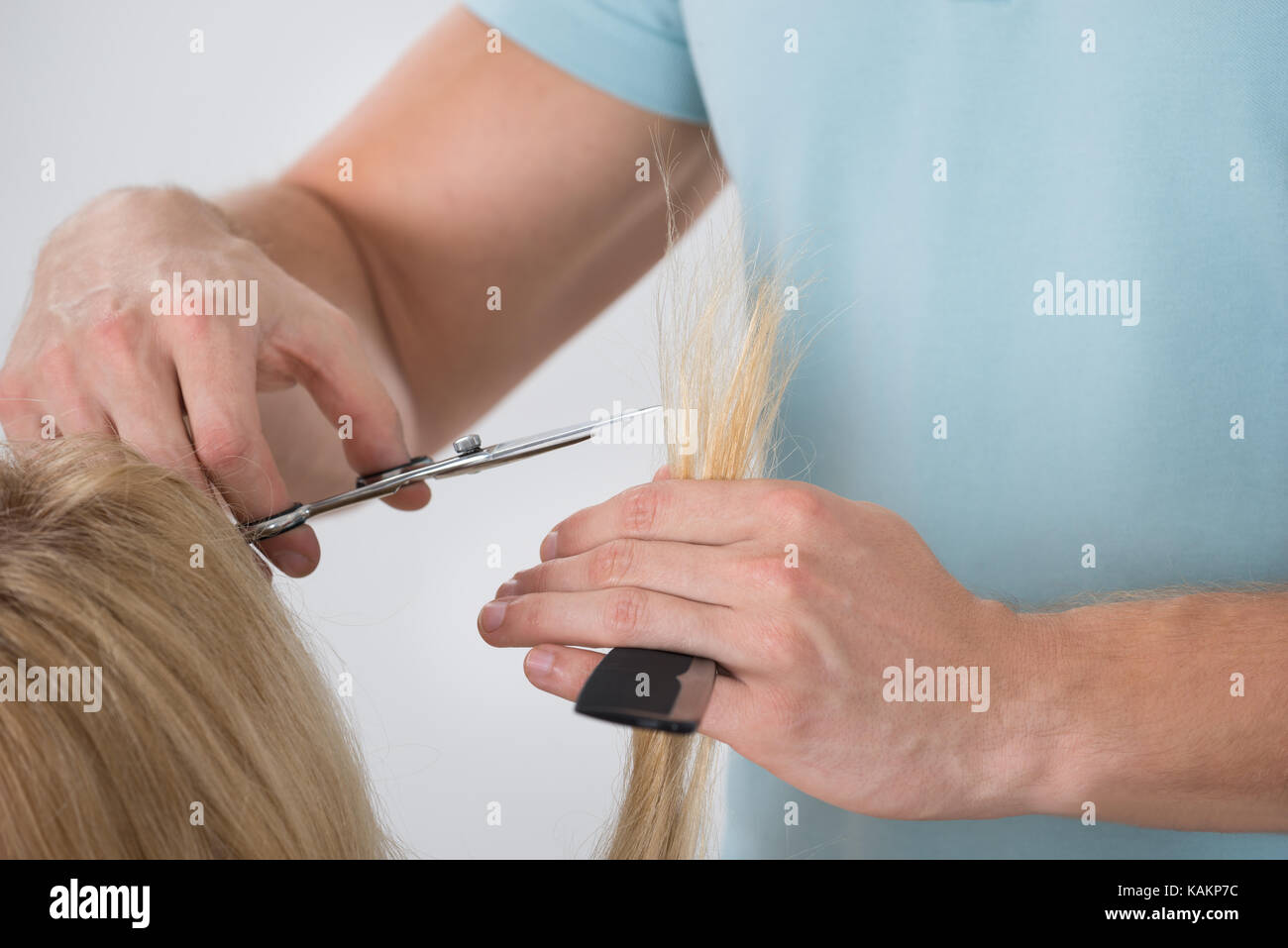 Zugeschnittenes Bild der jungen Frau, die ihr Haar durch männliche Kommode, die im Salon cut Stockfoto