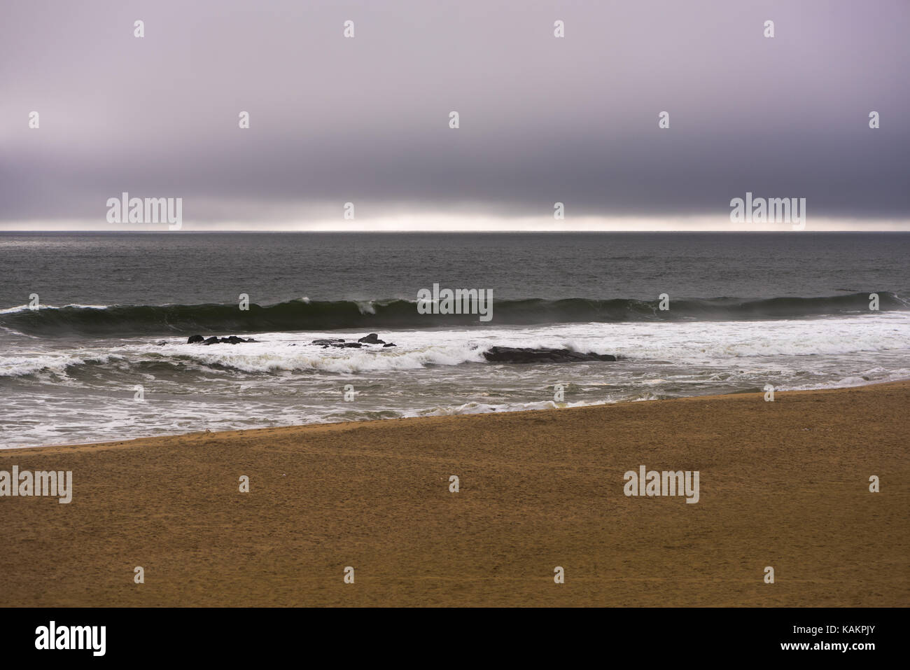 Nebeliger Morgen am Strand mit einem Sturm nähert sich Stockfoto