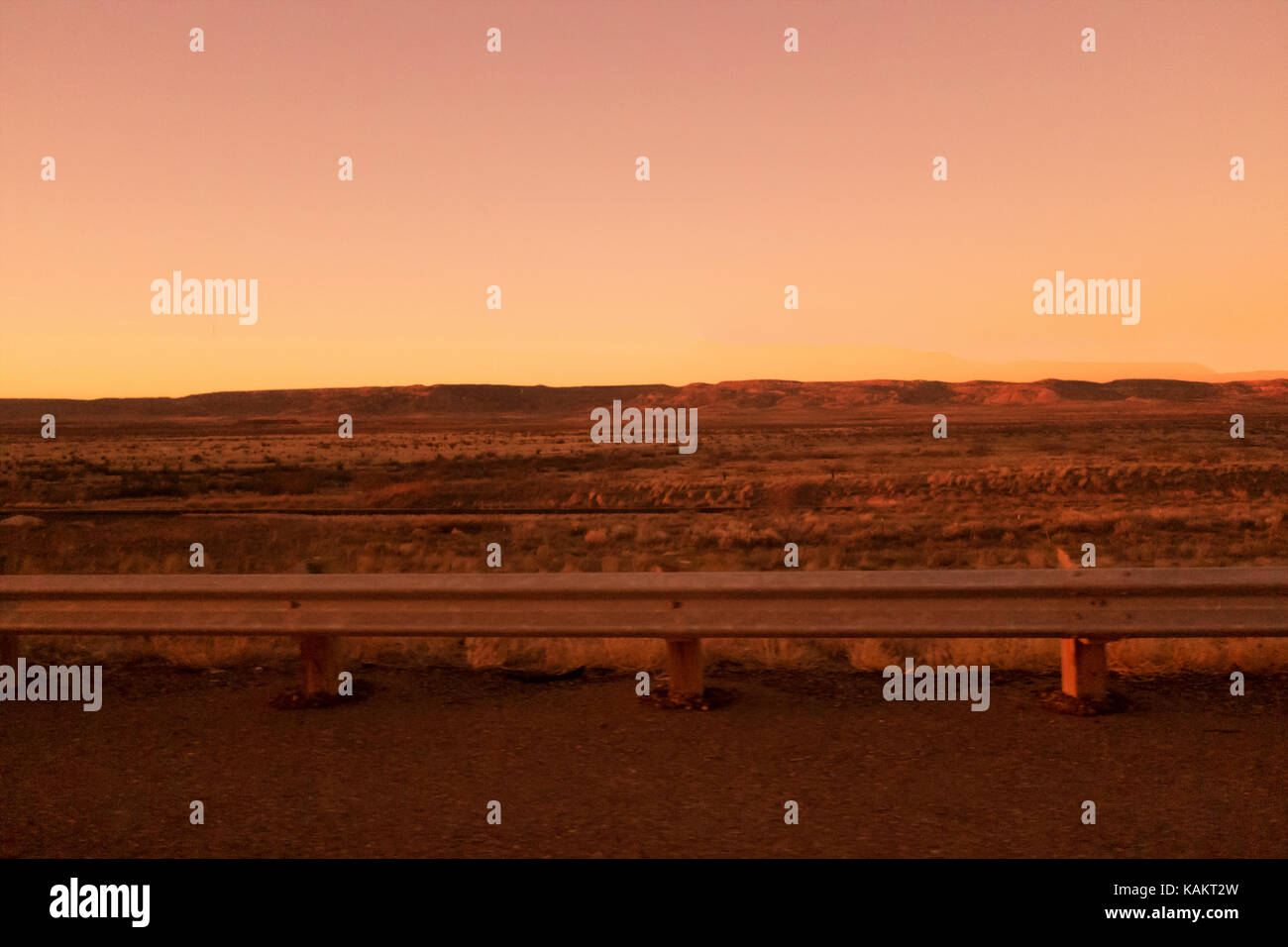 Eine felsige Ebene mit einem orangefarbenen Sonnenuntergang überspreizung das Land. Stockfoto