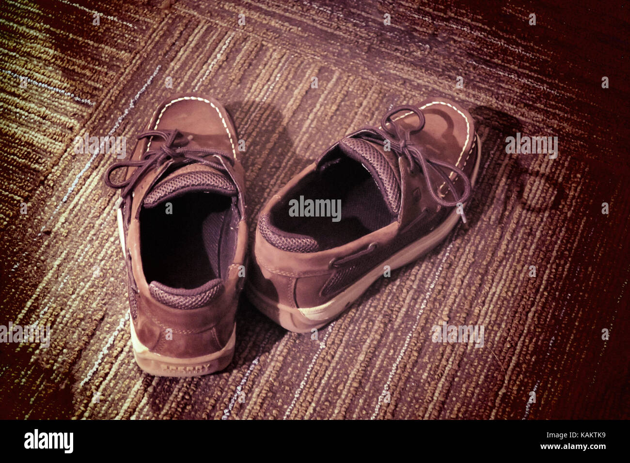 Ein paar junge Penny Loafer mit einem braunen Wirkung auf die gestreiften Teppich. Stockfoto