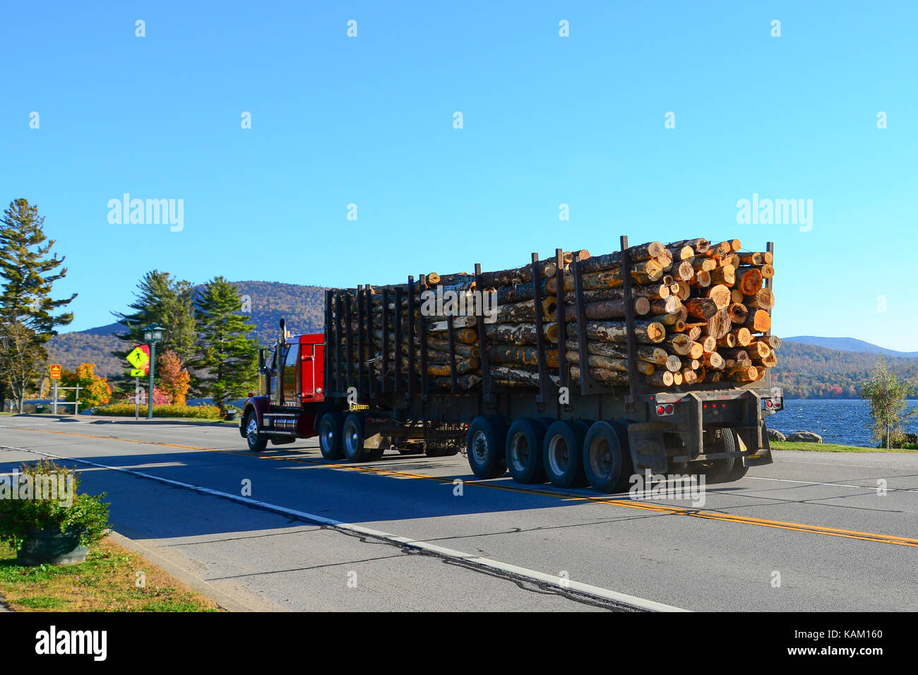Traktoren Anhänger Lkw mit Logs vorbeifahren See angenehm in den Adirondack Mountains geladen. Stockfoto