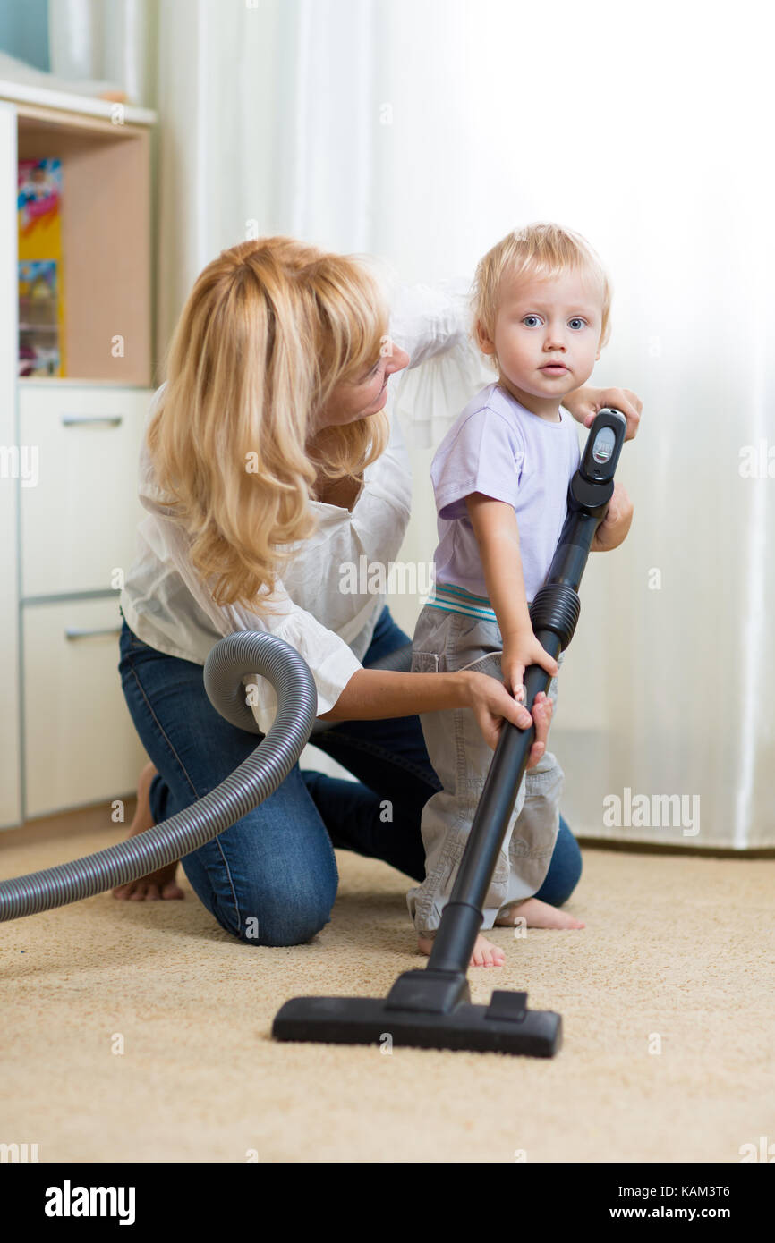Reinigung der Zimmer zusammen - die Mutter und ihr Kind Sohn mit Staubsauger absaugen Stockfoto
