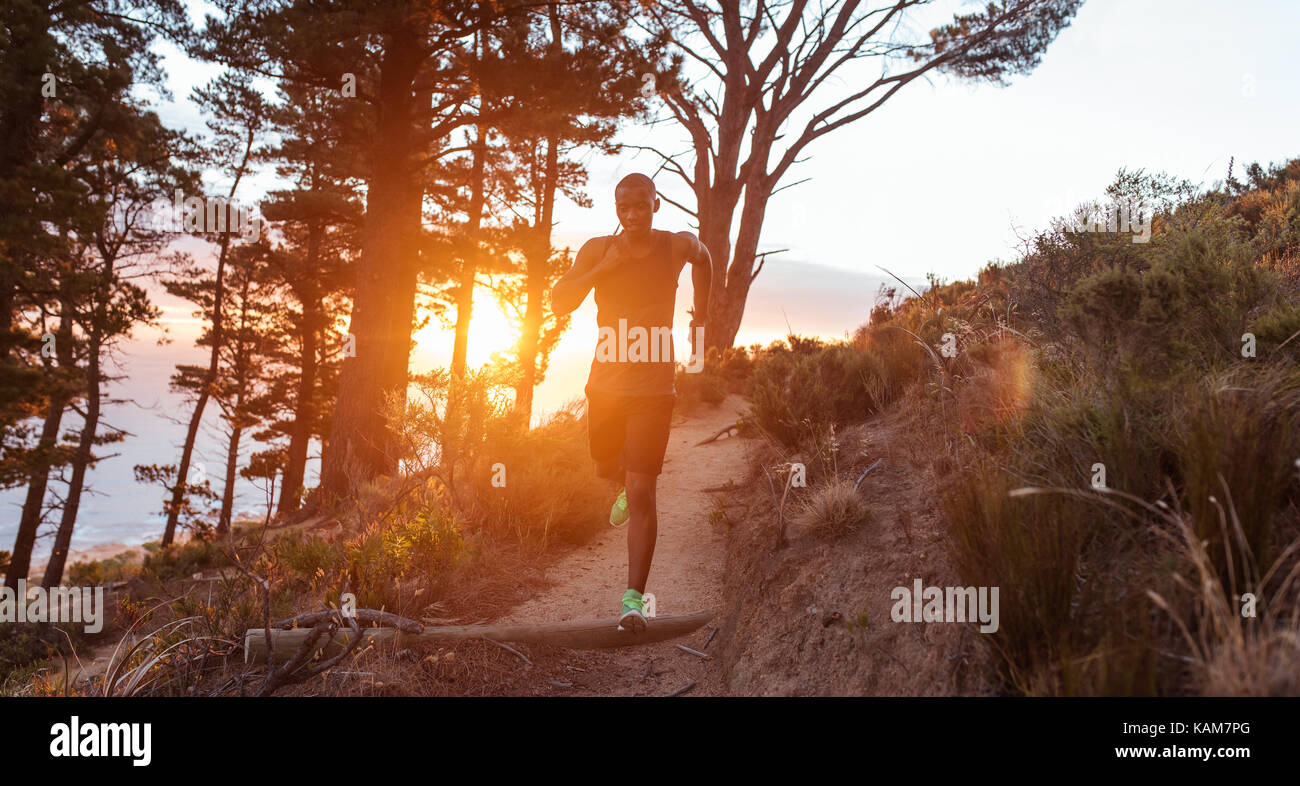 Junger Mann auf einem Hügel Trail in der Dämmerung Stockfoto