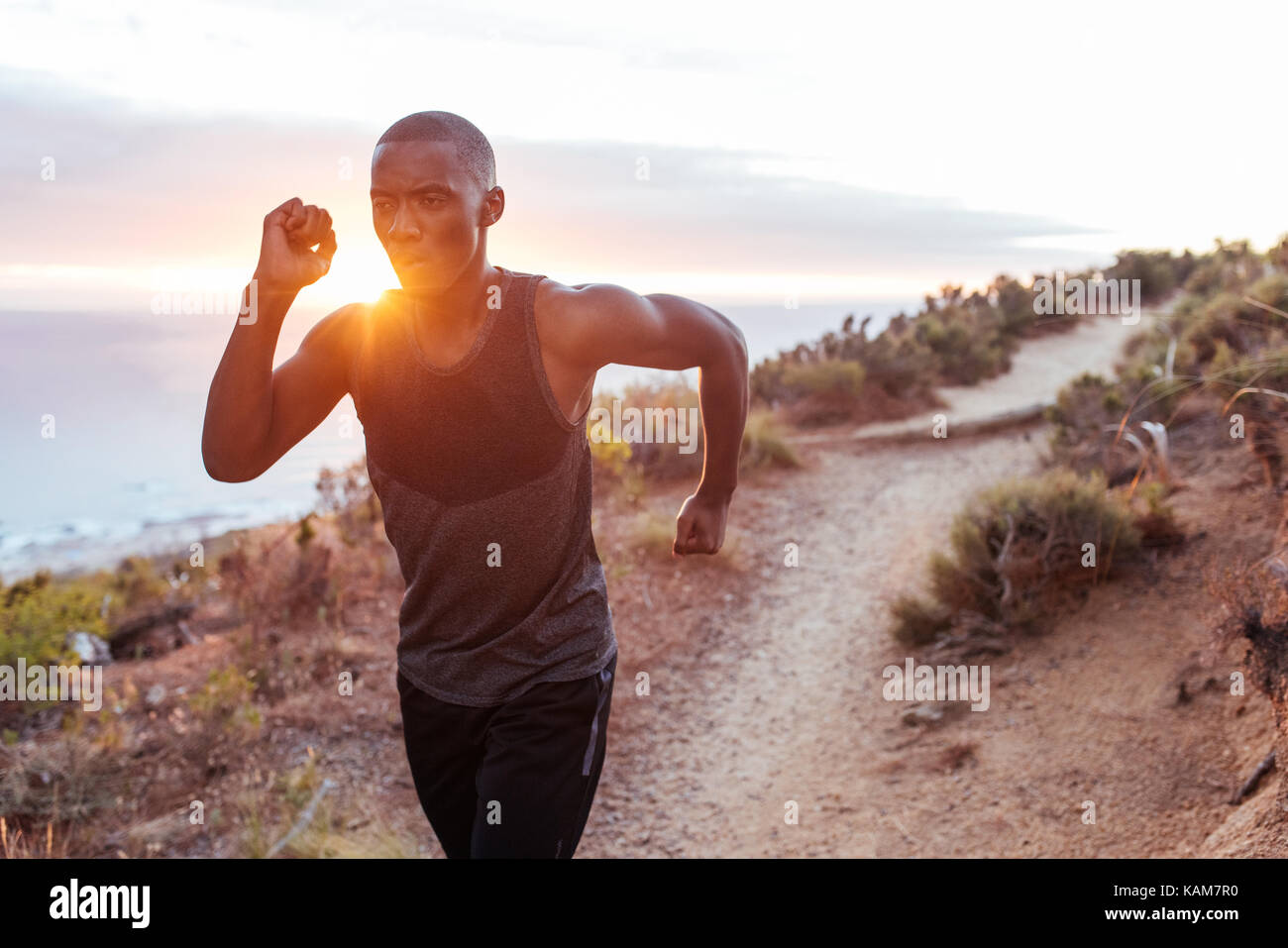 Passen junge Mann, der allein lief entlang ein Oceanside Trail Stockfoto