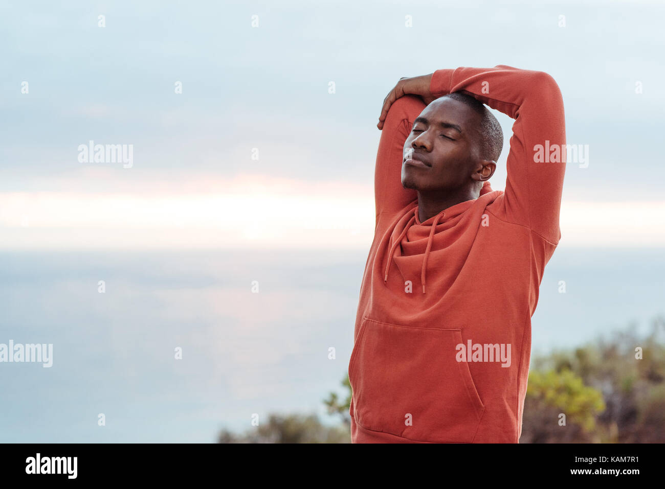 Junge afrikanische Menschen ausdehnen, bevor ein Lauf entlang der Ozean Stockfoto