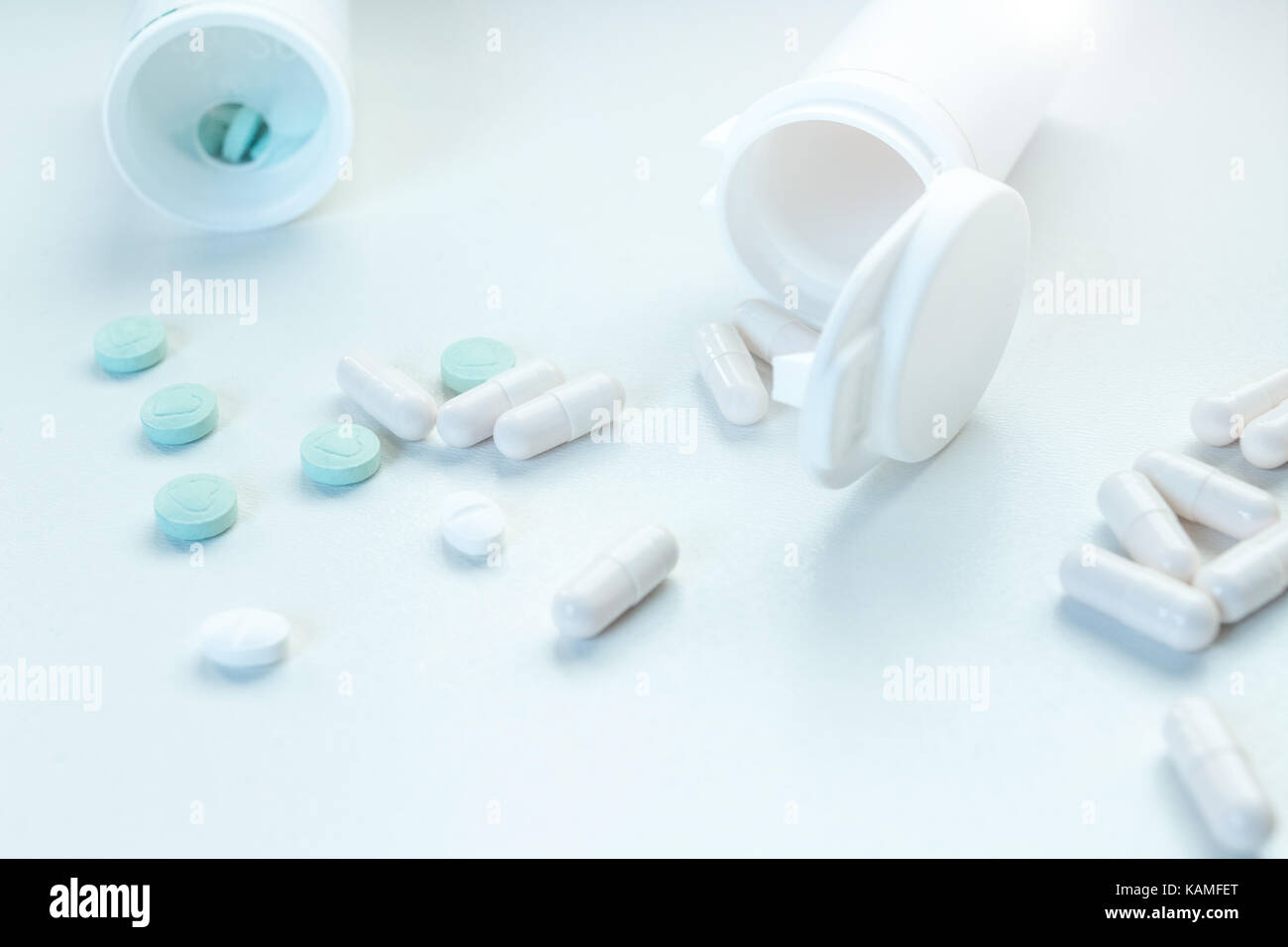 Weiße Kapseln und Tabletten RX Medikation Blau auf weißem Hintergrund isoliert, Container verschüttet Stockfoto
