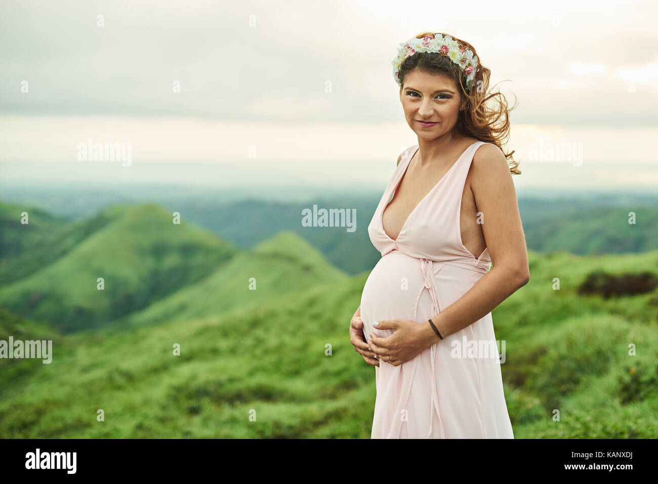 Schwangere junge Frau trägt Kleid im Freien in natürlichen, grünen Hintergrund Stockfoto