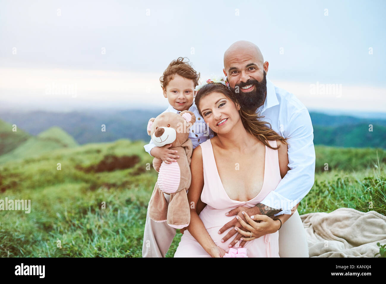 Junge, glückliche Familie sitzen auf Gras im Unscharfen natürlichen Hintergrund Stockfoto