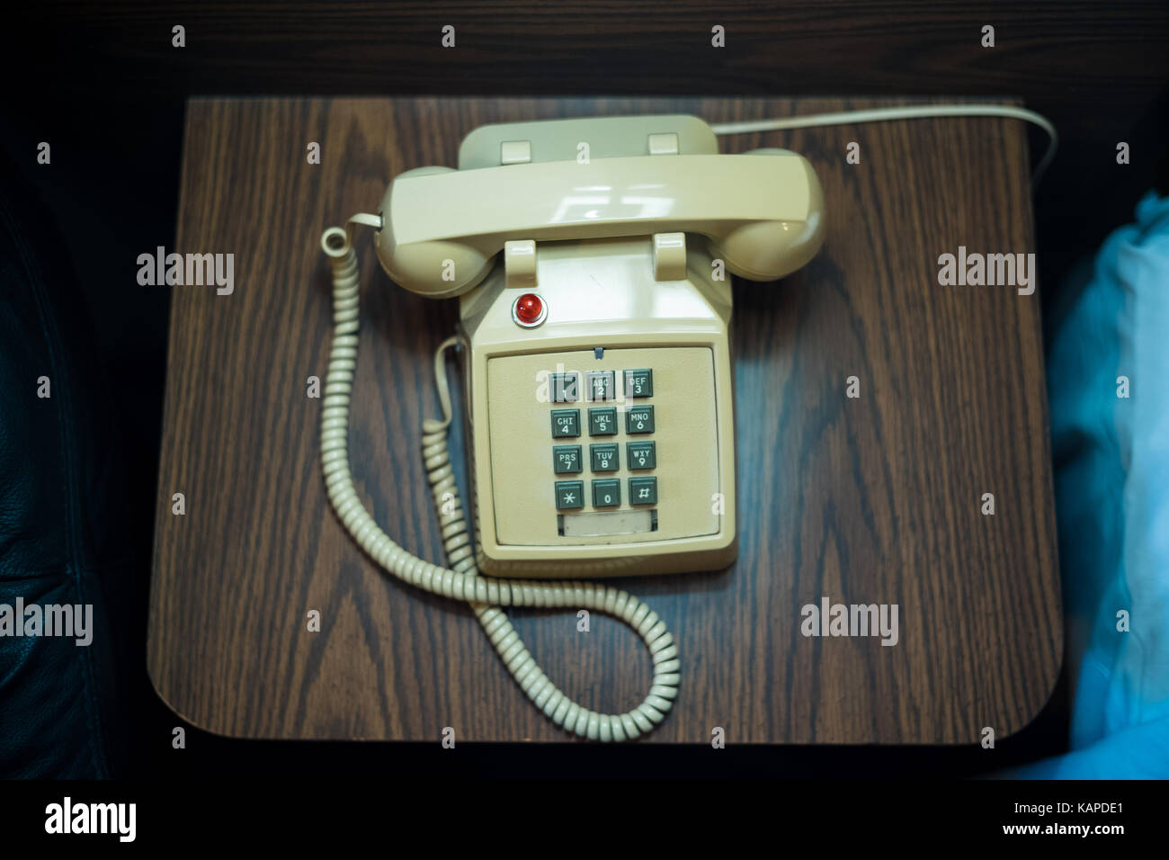 Ein altes Telefon sitzt neben einem Bett im Motel. Stockfoto