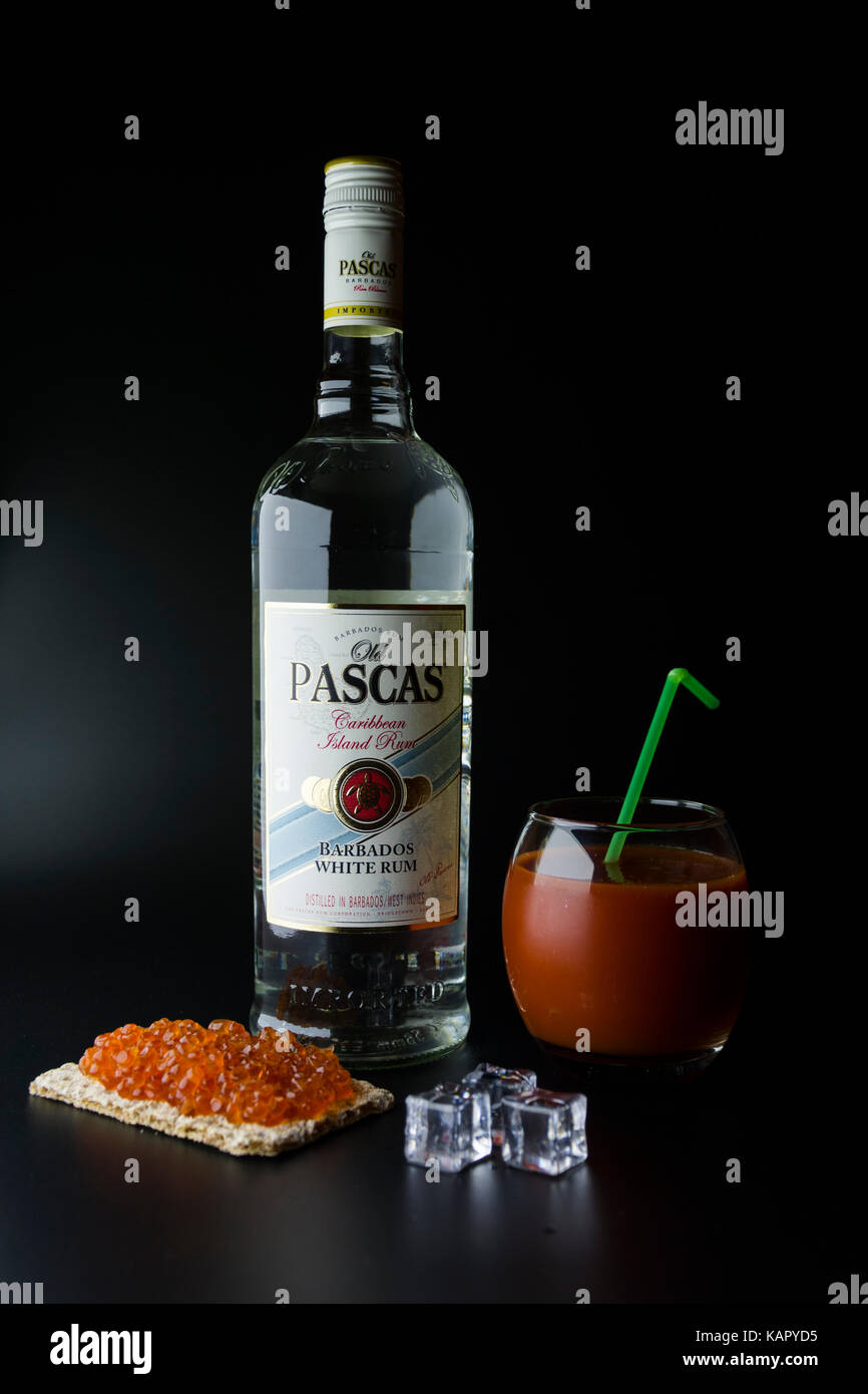 TIRASPOL, MOLDAU - 5. JUNI 2016: Karibische weiße Rum-Flasche Old Pascas auf schwarzem Hintergrund mit rotem Kaviar-Toast, Eiswürfeln und einem Glas Blood Ma Stockfoto