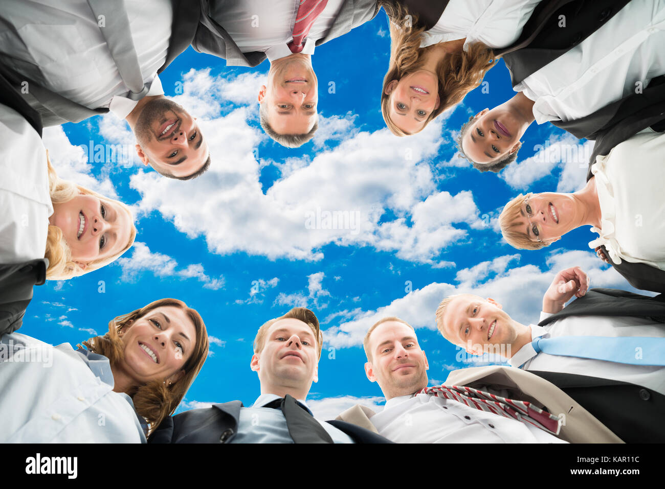 Direkt unter Portrait von vielfältigen Geschäft Leute bilden huddle gegen Sky Stockfoto