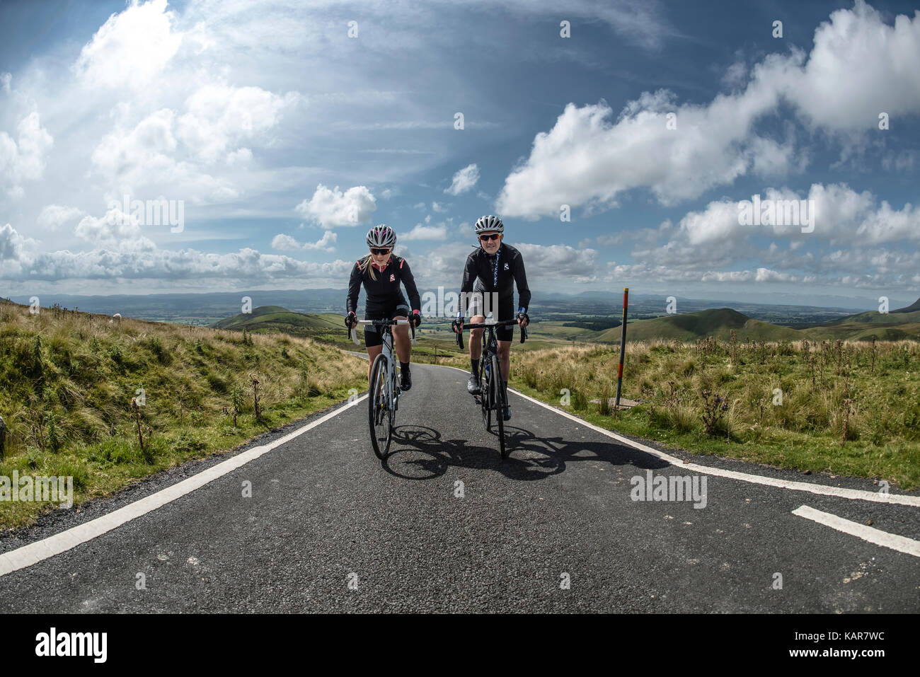 Radfahren Paar klettern Große Dun fiel in den Pennines, Cumbria, Großbritannien Stockfoto
