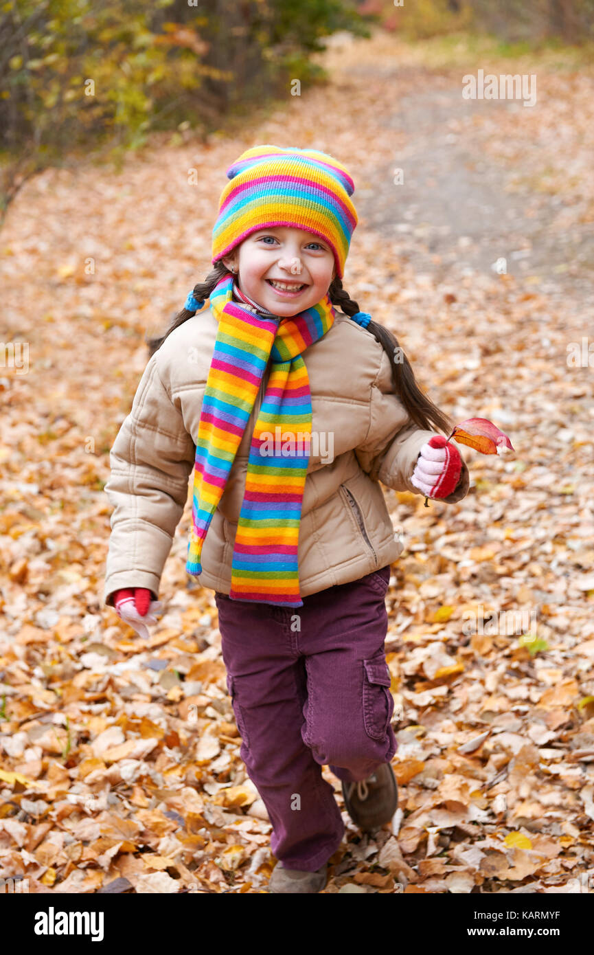 Kind Mädchen läuft auf einem Wanderweg im Herbst Wald durch Laub Hintergrund Stockfoto