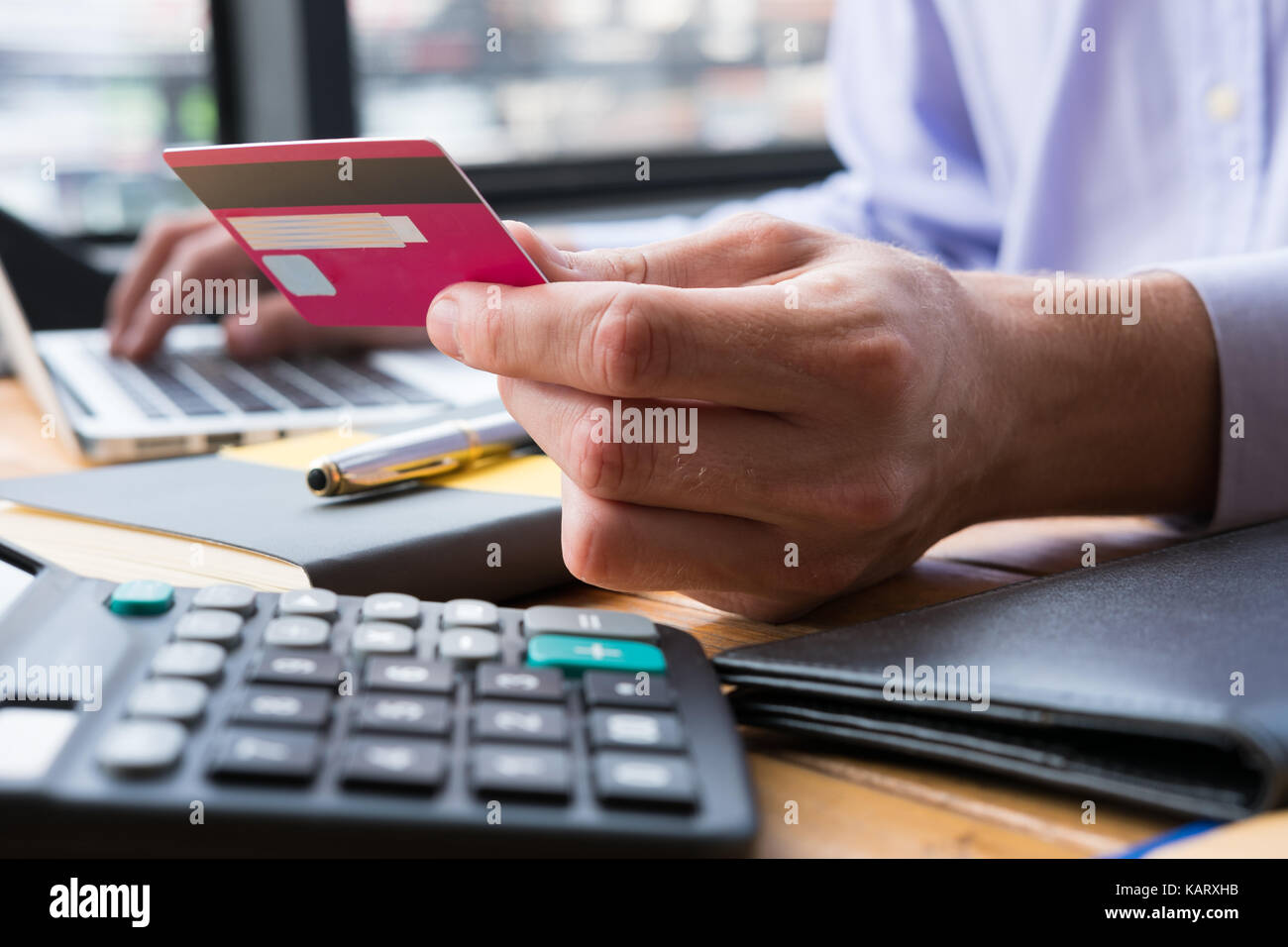 Geschäftsmann holding Kreditkarte Eingeben von Nummern auf Laptop Tastatur im Büro. Mann kaufen Waren & Bezahlung im Internet. Online Shopping, Stockfoto