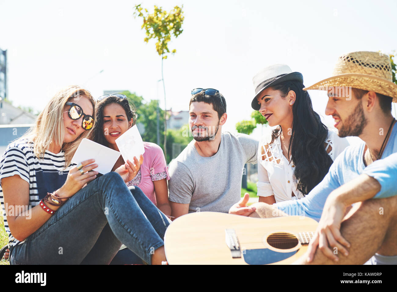 Glückliche junge Freunde mit Picknick im Park. Sie alle sind glücklich, Spaß, lächelnd und Gitarre spielen Stockfoto