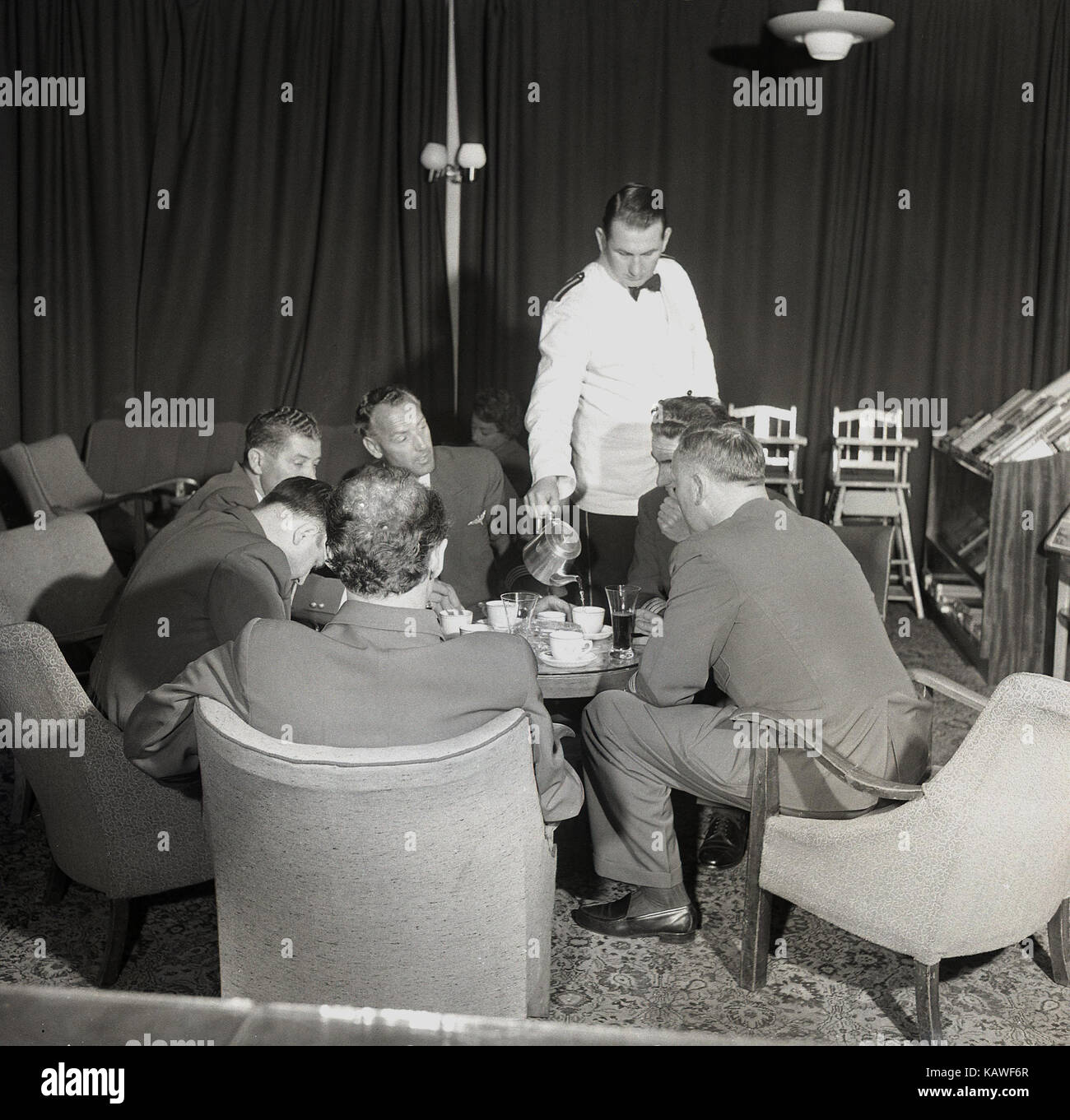 1950, historische, männlichen Piloten und Crew zusammen sitzen in einer Flughafen-lounge vor einem Flug, der Kaffee von einer weiß beschichteten uniformierte Kellner, Dublin, Irland. Stockfoto