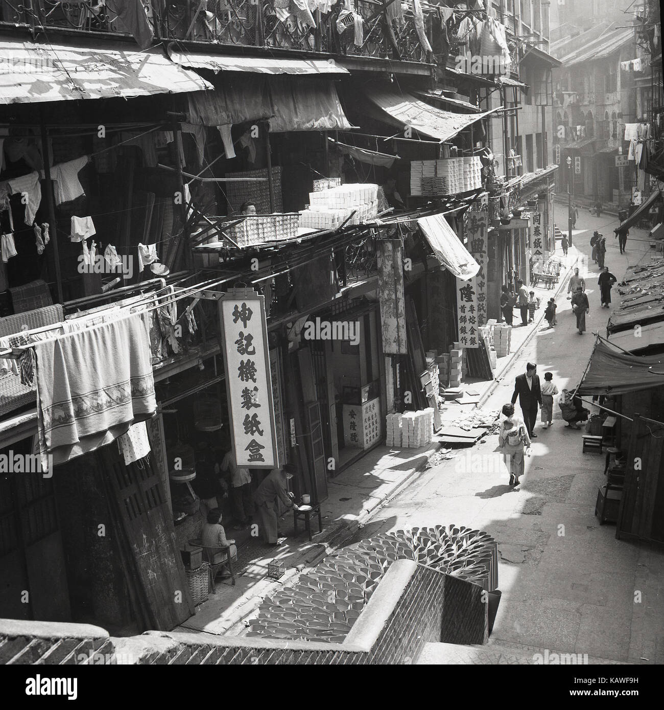1950er Jahre, historische Bild von Hong Kong mit einer in der Regel stark befahrenen Straße mit so genannten "hophouses', Mixing business ang leben, sehen wir kleine Anbieter und Abschaltdruck Inhaber auf der Straße neben einem Fußgängerweg und überfüllt, Open-Air-Wohnzimmer Unterkunft oder Residenzen. Stockfoto